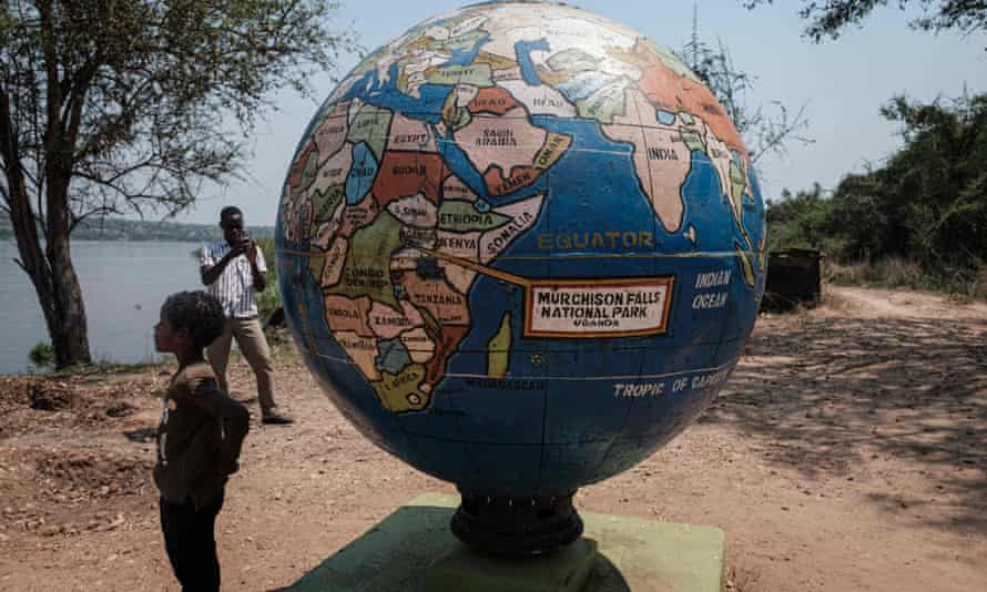 A boy stands by a globe statue at the Murchison Falls national park in Uganda.