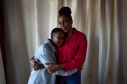 A middle-aged African woman and a teenager hug each other