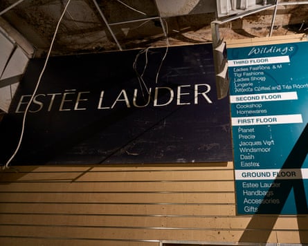 A wall with a large sign for Estée Lauder and a floor guide attached
