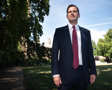Robert Jenrick stands on a path in a park in Millbank, central London, in the sunshine