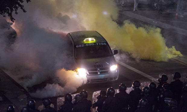 A taxi driver becomes trapped as police pepper spray and tear gas demonstrators after a rally by Donald Trump in Phoenix.