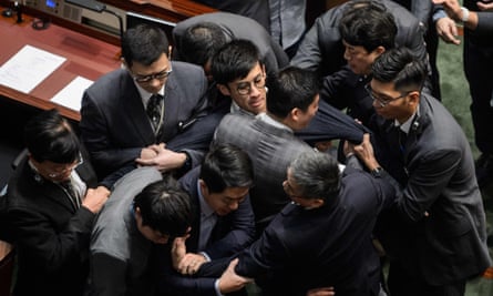 Leung (centre, wearing glasses) is restrained by security after attempting to read out his oath of office.