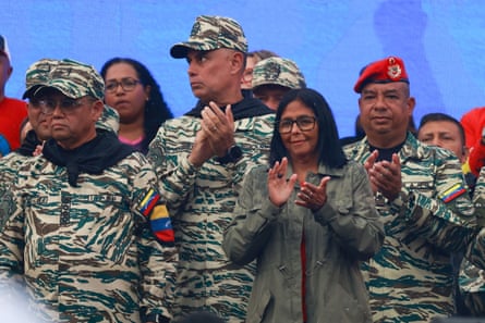 Delcy Rodríguez applauding at a military rally, standing in front of military personnel