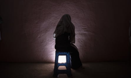 A silhouette of a rape survivor from Tigray sitting on a stool in a dark room
