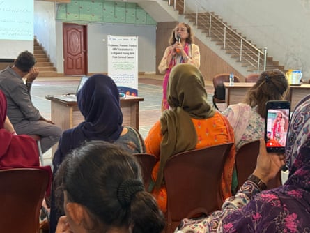 A woman stands in a hall before a seated audience
