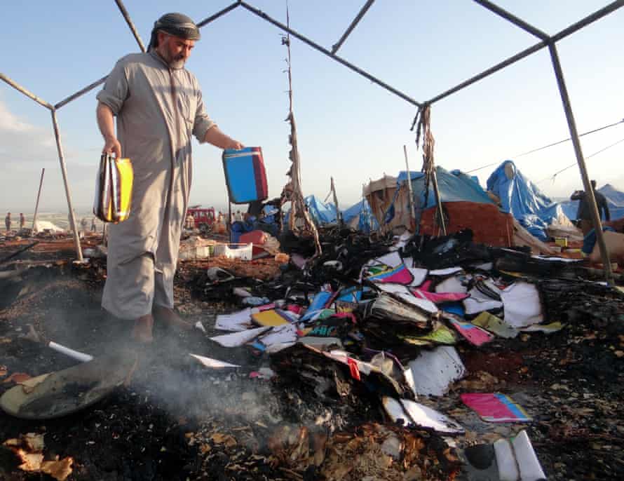 A man inspects the damage at Syria refugee camp