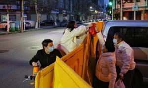 People deliver food to residents over a barrier set up to prevent people from entering or leaving a residential community in Wuhan.