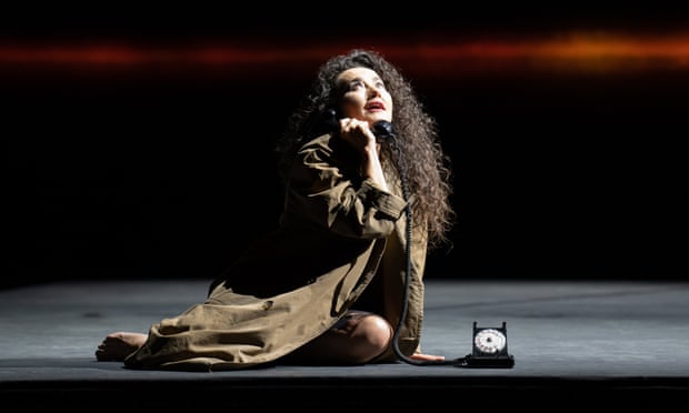 Stéphanie d’Oustrac as Elle, holding the receiver of an old-fashioned black dial phone