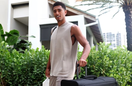 Bellingham pulls a suitcase while wearing a sleeveless knit