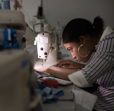 A woman sitting at a sewing machine stitching a garment