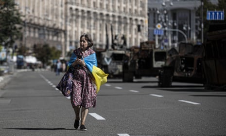 A Ukrainian woman wearing a Ukraine flag walks through Kyiv on independence day,