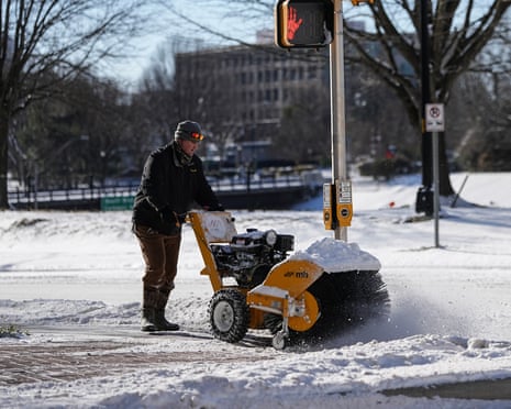 man snowblows sidewalk