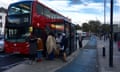 A floating bus stop on the CS2 cycle route in Mile End, east London:  a red London bus is stopped and people are getting on from an area which is separated from the main pavement by the cycle lane