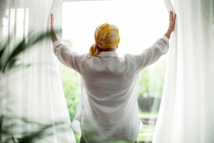Rear view of a woman opening curtains