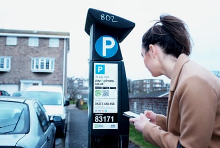 A woman tries to pay for parking via a parking app advertised on the ticket machine