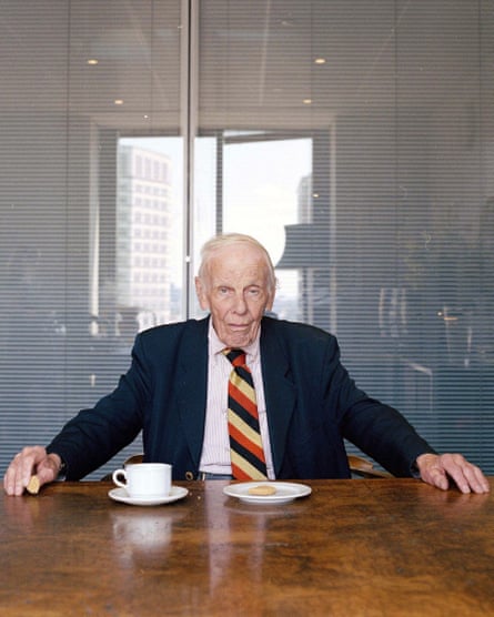 Bill Deedes sitting at a table in his office with a tea cup and a saucer with a biscuit