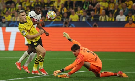 Borussia Dortmund's keeper Gregor Kobel (right) saves from Paris St Germain's Ousmane Dembele (centre).