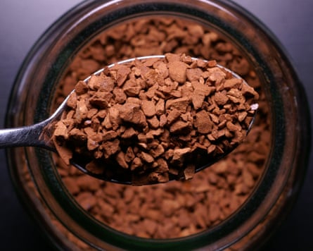 Teaspoon of instant coffee from above with the jar of coffee below.