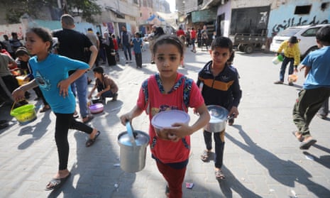 Palestinian children receive food from an emergency kitchen in southern Gaza