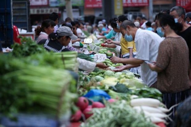 People buying vegetables at a market in north-east China’s Liaoning province