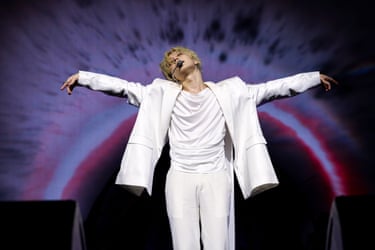 Taemin performs on stage in a white suit against a purple background