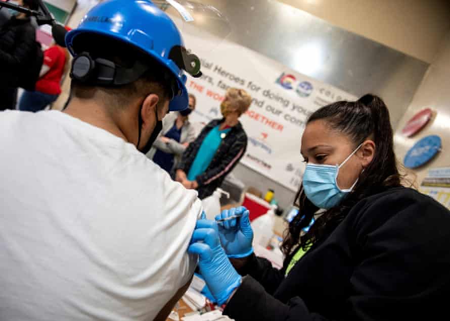 Luis Arellano receives his first dose of the Covid vaccine from Liz Negron, a Kaiser medical assitant, during a clinic in Greeley, Colorado.