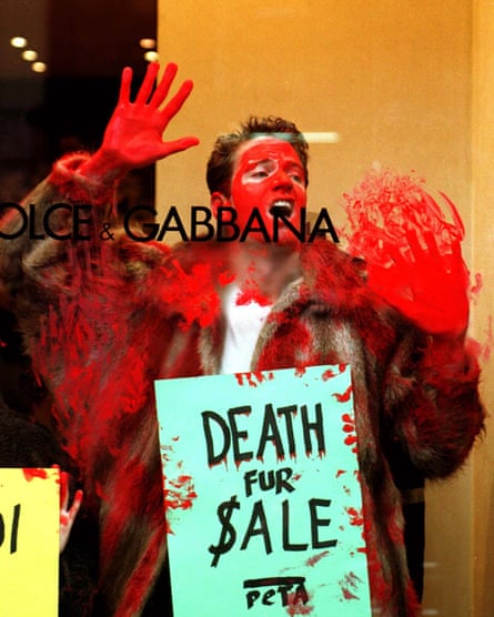 An activist marks a Dolce & Gabbana glass storefront with red paint