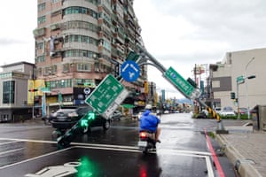 A man rides a scooter beneath the pole of traffic lights that have crashed into the road