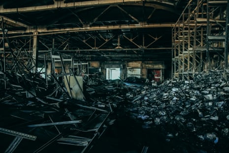 Charred books and twisted metal litter the floor of a warehouse
