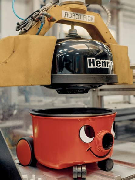A robot attaching a lid to a Henry vacuum cleaner on the assembly line.