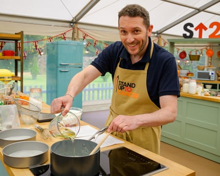 A smiling Bake Off contestant pours liquid from a jug into a saucepan on a hob