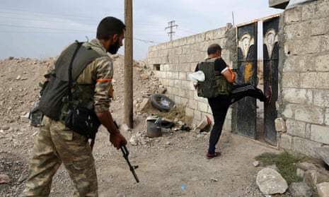 Turkey-backed Syrian fighters break open the front door of a house in Ras al-Ayn, a town now abandoned by Kurdish forces. 