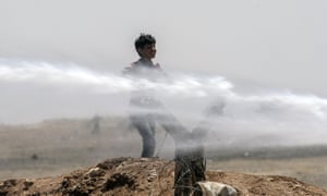A Syrian boy stands as Turkish soldiers use water cannon to push refugees away from fences in Akcakale at the Turkish border near the Syrian town of Tal Abyad.