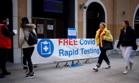 People walk past a sign directing people to a rapid lateral flow Covid-19 testing centre at London Bridge station