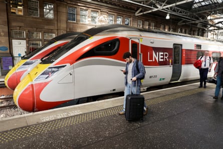 Two LNER high-speed trains lined up at platforms at Waverley railway station in Edinburgh. They are white with red stripes and yellow noses.