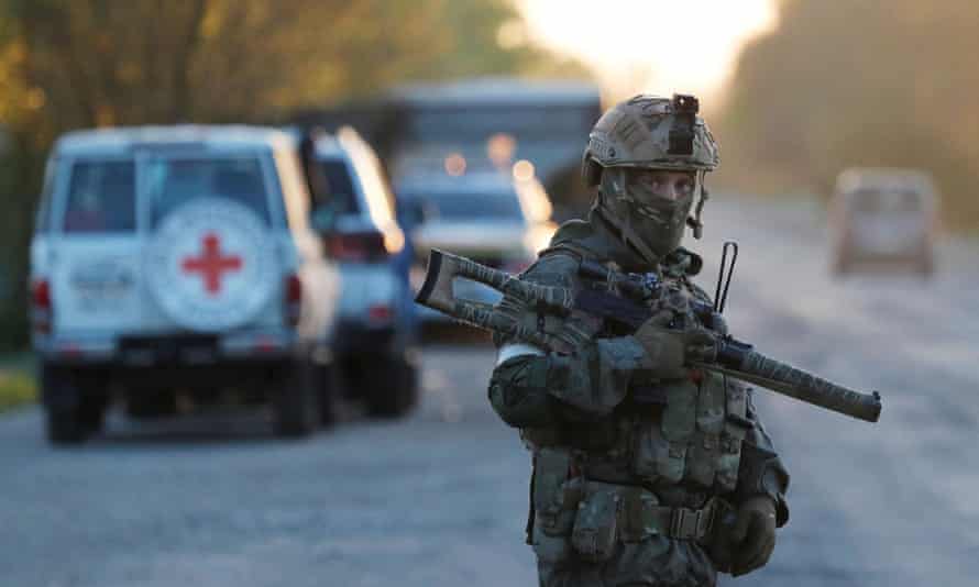 A service member of pro-Russian troops stands guard as civilians evacuated from Azovstal steel plant in Mariupol arrive at a temporary accommodation centre in the village of Bezimenne