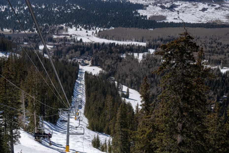 A snowy tree-filled landscape is seen from the top of a chairlift.
