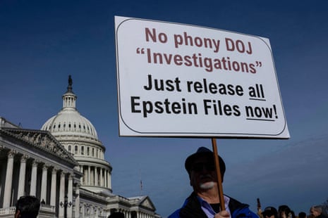 a person holds a sign that reads 'no phone DOJ investigations just release all Epstein files now'