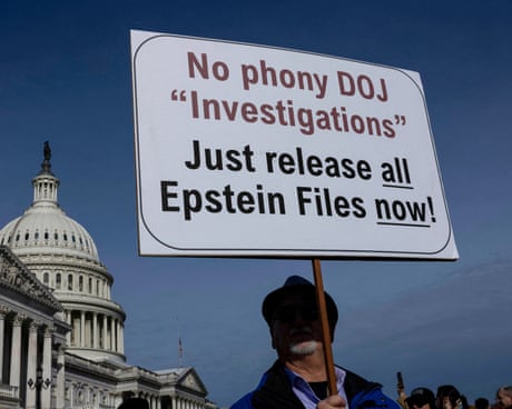 a person holds a sign that reads 'no phone DOJ investigations just release all Epstein files now'