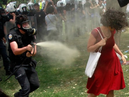A Turkish riot policeman uses tear gas against a woman as people protest against the destruction of trees in a park brought about by a pedestrian project, in Taksim Square in central Istanbul May 28, 2013.I