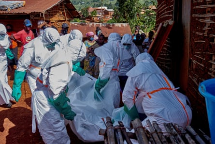 Red Cross workers wearing personal protective equipment (PPE) retrieve the body an unidentified man who died of Ebola from his house