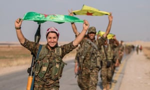 Kurdish fighters carry their parties’ flags in Tel Abyad after capturing the town from Islamic State last year.
