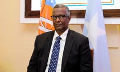 Grim-faced Somali man pictured in front of flags