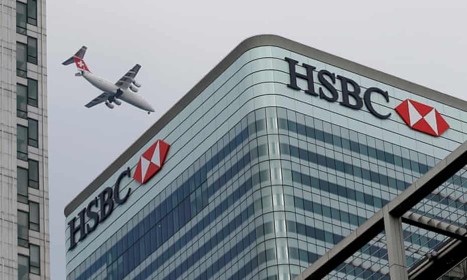 An aircraft flies past the HSBC headquarters building in the Canary Wharf financial district in east London.