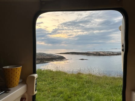 View through a doorway of a body of water, grass and scudding clouds