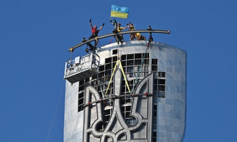 Steeplejacks wave a flag after they install the Ukrainian official coat of arms on 6 August.