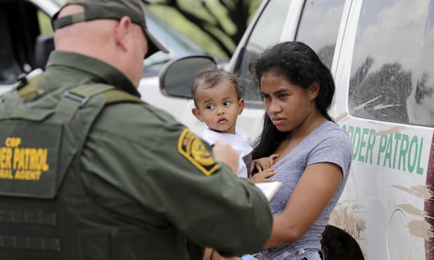 A mother migrating from Honduras holds her 1-year-old child as she surrenders to US Border Patrol agents after illegally crossing the border, near McAllen, Texas. 