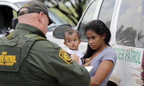 In this photo from 25 June 2018, a mother migrating from Honduras holds her one-year-old child as she surrenders to US border patrol agents after illegally crossing the border, near McAllen, Texas.
