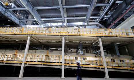 Person walks past electric car battery production line  inside a gigafactory