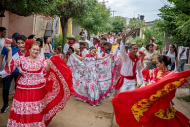 People in colorful traditional c lothing dance in the street